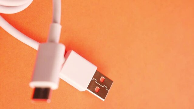 Vertical video of white usb cable on orange background