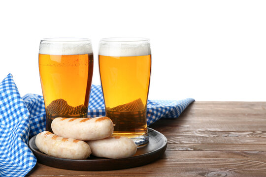 Glasses of cold beer and plate with sausages on table against white background. Oktoberfest celebration