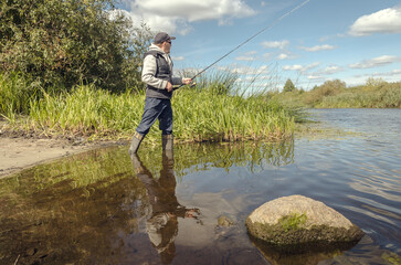 Man catching fish, pulling rod while fishing.