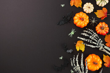Experiencing the unearthly aura that accompanies Halloween. Top view photo of scary skeleton hands, pumpkins, autumn leaves, creepy insects on black background with ad zone