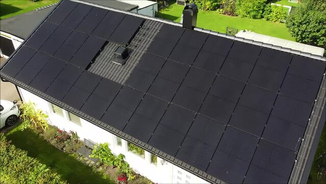 Drone circling over villa with solar panels and electric car charging