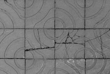 Broken and weathered square paving stones or blocks with geometric shapes outdoors, viewed from above. High resolution full frame textured background in black and white.