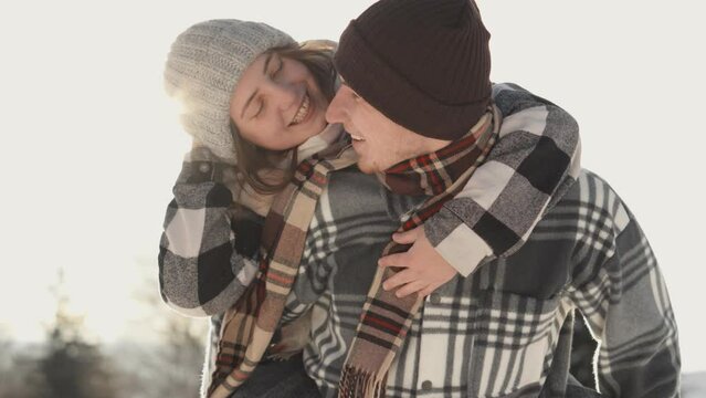 Tenderness and affection on their faces testify to how they bloom together even on cold winter day. Winter romance couple in love against background sun. Often spending time and leisure time together