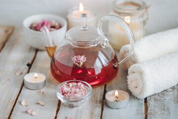 Obraz na płótnie Canvas Aromatherapy. Organic natural floral, plant ingredients for spa treatment in salon. Rose petals, essential oil, burning candles, towels, delicious herbal tea, Atmosphere of relax, detention.