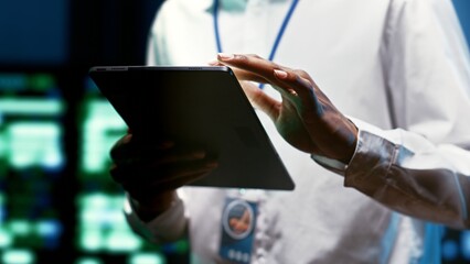 System administrator using tablet to check high tech facility security features protecting against unauthorized access, data breaches, phishing attacks and other cybersecurity threats, close up
