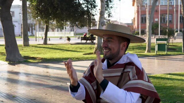 var&oacute;n joven con traje de huaso aplaudiendo al ritmo del baile cueca en la plaza de la ciudad