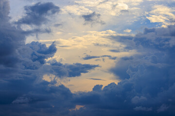 Golden light through towering blue clouds as storm approaches at sunset