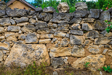 Old rustic fence made of stones collected without mortar. Background with selective focus