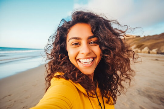 Beautiful young indian woman enjoying a day on the beach while smiling and making a picture