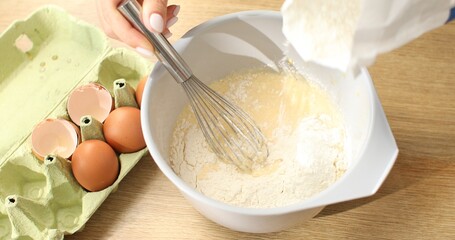 Flour is added to a bowl with beaten eggs. Making faffels or pancakes. Food preparation.