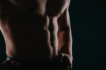 Silhouette photo of strong man showing his abs in studio. Partial shot