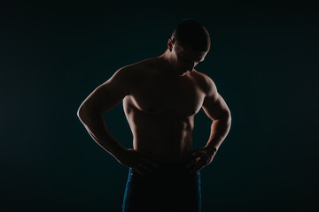 Fototapeta na wymiar Fit male sports person posing in studio. He is looking at his abs.
