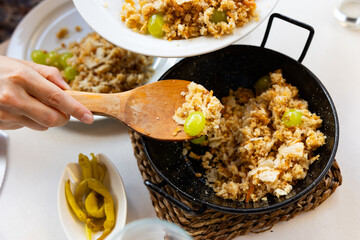 Female waitress hands lay out on plates traditional dish of Aragonese shepherds - migas, decorated...