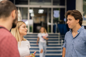 University students discussing after exam at the yard outdoors. Male student realizing he wrote a wrong answer on the test while talking with his blonde female colleague
