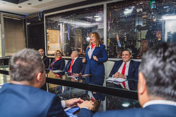 Mature businesswoman sharing fun experience in meeting with her business partners. They are having fun and laughing.