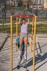 Man helping his girlfriend doing push ups in the park