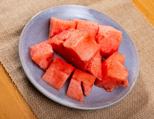 Ripe watermelon pieces dished up in a plate on the laid table in restaurant