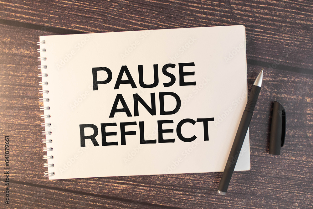 Poster pause and reflect text on sticker on diary with keyboard and pencil.