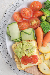 Antioxidant vegetable salad served on a white plate with guacamole and cheese spread on toast accompanied by greek yogurt and chia seeds.