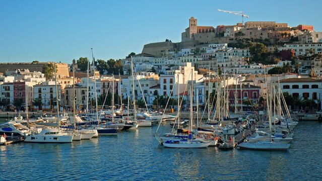 Luxury yachts and boats by Eivissa Harbour Port with buildings in background. Big yachts of millionaires and billionaires enjoying vacation on the Ibiza Island in Spain.