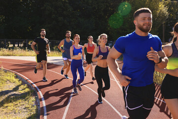 Group of people running at stadium on sunny day