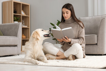 Woman reading book with cute Labrador Retriever dog on floor at home. Adorable pet