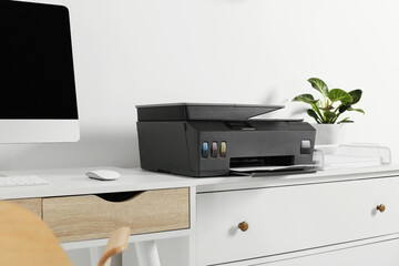 Modern printer with paper on chest of drawers indoors