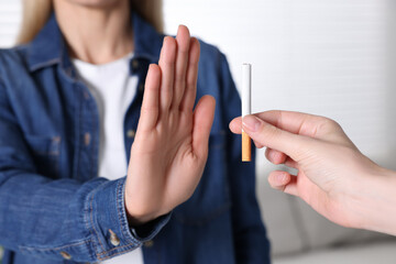 Woman refusing cigarette on light background, closeup. Quitting smoking concept