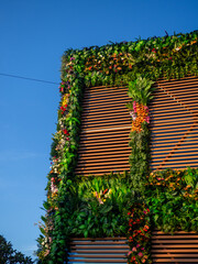 Decoration of the facade of the building with artificial flowers. Building in flowers. Resort place. Facades of buildings. Interesting design idea.