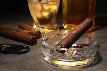 Cigars, ashtray, whiskey and cutter on grey table, closeup