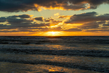 Evening landscape of sea water waves crushing on sandy beach at sunset