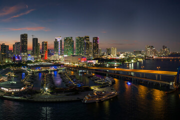 Fototapeta premium Miami marina harbor and skyscrapers of Brickell, city financial center. Skyviews Miami Observation Wheel at Bayside Marketplace with reflections in Biscayne Bay water and US urban landscape at night