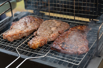 tasty steak on a bbq grill with smoking smoke and fire and glowing coals. High quality photo
