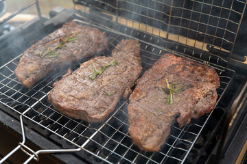 tasty steak on a bbq grill with smoking smoke and fire and glowing coals. High quality photo