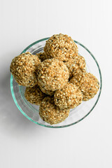 Healthy energy balls with sesame in glass bowl on white background