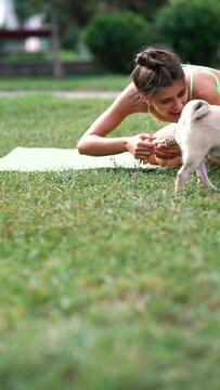 Engaging in outdoor play, a pretty girl in athletic clothing enjoys spending time with her pug dog in a summer park.