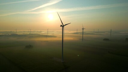 SIlhouette of rotating windmills in Poland on an early foggy morning. Drone dolley shot