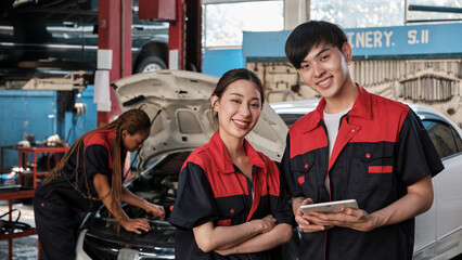 Two Asian professional mechanics, male engineer and partner smile and look at camera, inspect...