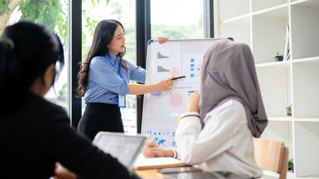 A beautiful Asian businesswoman is presenting her summarized financial data to her team