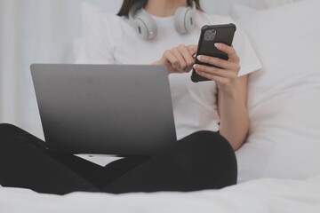 Efficient Young Millennial Girl Sitting on a Bed in the Morning, Uses Laptop Computer and Eats Croissants and Drinks Coffee for Breakfast