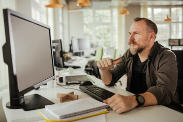 Fototapeta na wymiar Middle aged caucasian man using a computer at a office job