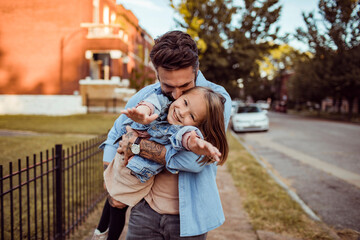 Young caucasian father holding his daughter in the street of a suburb