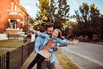 Young caucasian father holding his daughter in the street of a suburb