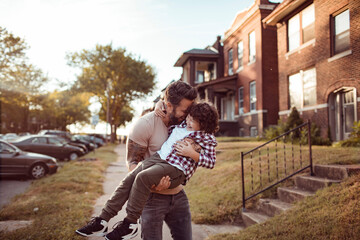 Young caucasian father holding his son in the street of a suburb