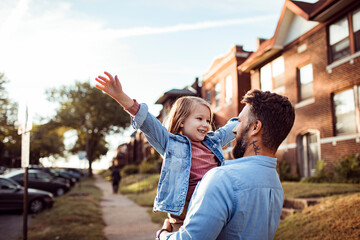 Young caucasian father holding his daughter in the street of a suburb
