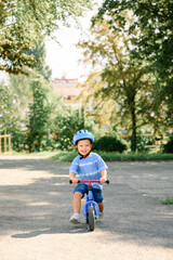 Happy child riding balance bike. Male toddler kid in helmet learning to ride on run bicycle