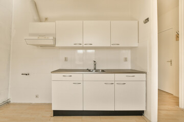 a kitchen with white cupboards and black counter tops on the floor in a small room that has wood floors