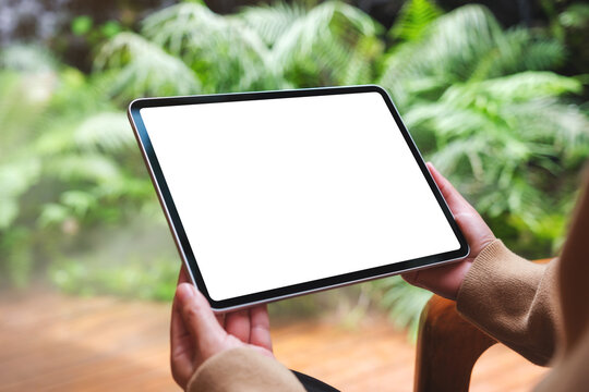 Mockup image of a woman holding digital tablet with blank white desktop screen in the garden