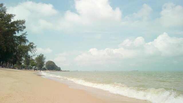 Daytime view of Pantai Puteri Beach in Malacca, Malaysia. Waves from the sea washing ashore and dissolving into the sandy beach.