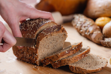 Close-up captures skilled slicing of dark bread.